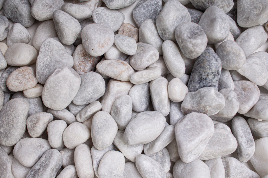 Carrara Marmor getrommelt 15-25 mm – Nahaufnahme trocken (links) und nass (rechts) im Vergleich
