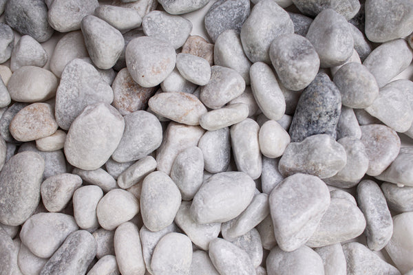 Carrara Marmor getrommelt 15-25 mm – Nahaufnahme trocken (links) und nass (rechts) im Vergleich
