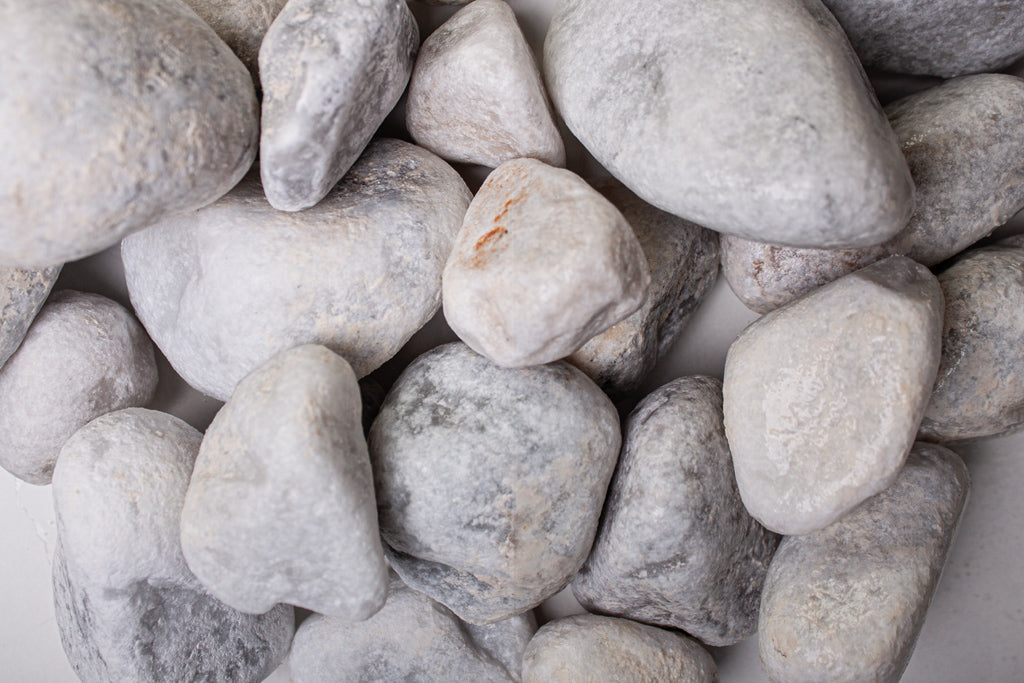 Carrara Marmor getrommelt 40-60 mm – Nahaufnahme trocken (links) und nass (rechts) im Vergleich