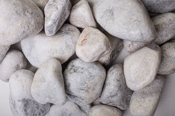 Carrara Marmor getrommelt 40-60 mm – Nahaufnahme trocken (links) und nass (rechts) im Vergleich